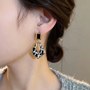 Boucles d'oreilles léopard géométriques avec bord doré et diamants sur modèle