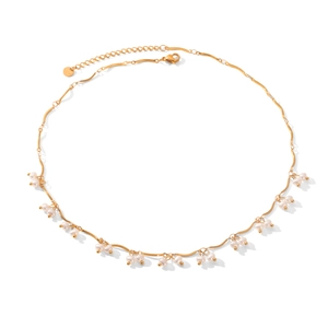 Detailed view of golden wavy chain necklace featuring delicate white hanging pearls