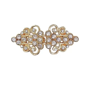Détail d'un clip de gilet vintage doré avec strass et motifs floraux gravés
