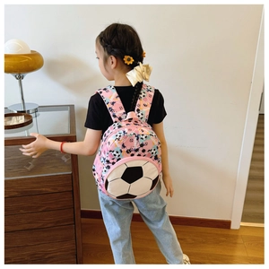 Rear view of a pink football themed backpack worn by a young girl in a home setting