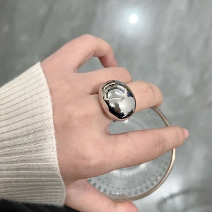 Close-up of a silver polished water drop ring on a hand holding a glass cup