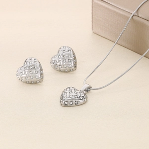 Macro shot of silver woven heart pendant and matching stud earrings on flat lay background