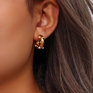 Close-up of 18K gold-plated C-shaped earrings with white pearls and zircons on a model