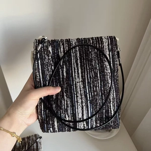 Detail of a retro black and white striped woven crossbody phone bag with thin rope strap