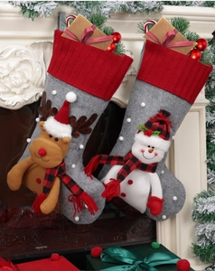 Detail of knit Christmas stockings with reindeer and snowman hanging on a cozy fireplace