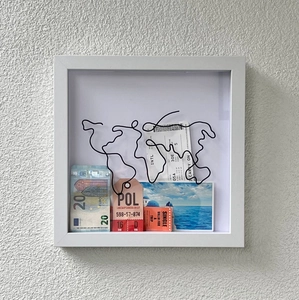 Detail view of a white shadow box featuring a wire world map and travel memorabilia
