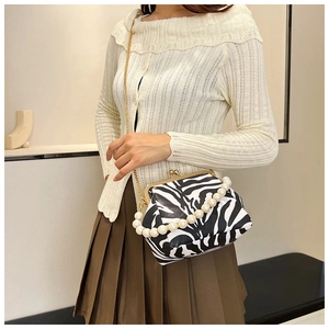 Detail of zebra pattern shoulder bag featuring pearl handle and golden chain strap