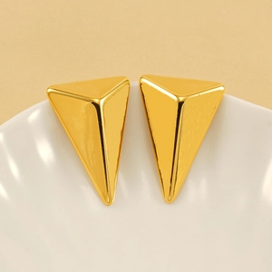Polished 18K gold plated stainless steel triangle stud earrings in a white ceramic dish