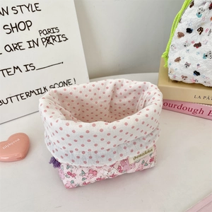 Close-up of quilted floral storage bag with pink polka dot lining and woven label