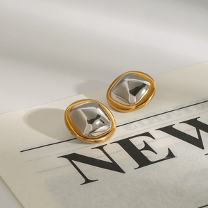 Macro detail of two-tone gold and silver rectangular earrings on newspaper