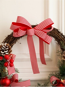 Close-up of rustic Christmas wreath with red ribbon bow, pine cones and warm LED lights