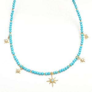 Detail of bohemian necklace with turquoise beads and gold star pendants on white background