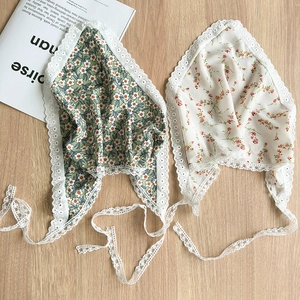 Floral lace-trimmed headscarves in green and white daisy patterns on a wooden surface