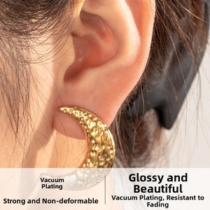 Macro shot of gold crescent moon earrings with a hammered texture and polished metallic finish