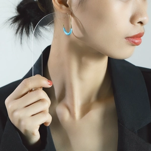 Detail of 18K gold titanium U-shape earrings with turquoise enamel on a model