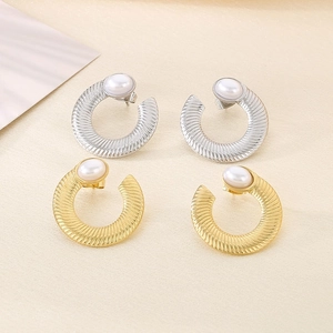 Macro detail of U-shaped rippled metal earrings with pearl inlay in gold and silver