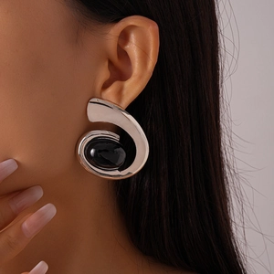 Gros plan de boucles d'oreilles spirales argentées avec pierre noire ovale