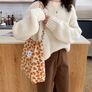 Detail of floral printed corduroy tote bag with orange flowers and shoulder strap