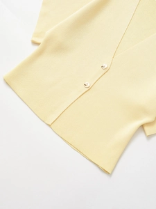 Close-up of yellow knit cardigan showing soft fabric texture and beige buttons details