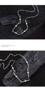 Macro detail of a silver ball and oval link necklace on a textured black background