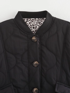 Detail of black quilted jacket featuring leopard print lining and retro brown buttons