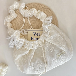 Détail du sac à main en dentelle blanche brodée avec fleurs et bandoulière à volants