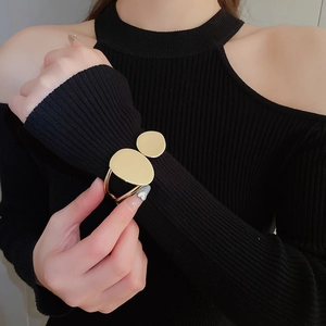 Close-up of golden irregular oval double-layer open bangle on a black knit sleeve