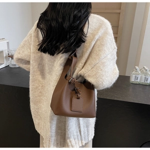 Close-up of brown litchi pattern bucket bag with adjustable strap and tag decoration