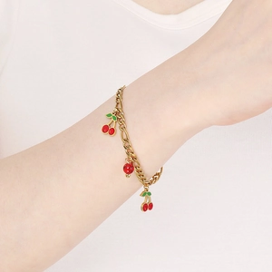 Close-up of 18K gold plated stainless steel bracelet with red cherry charm on wrist