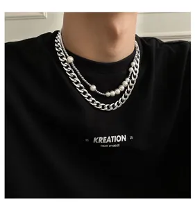 Détail d'un collier multicouche avec chaîne cubaine argentée et perles blanches