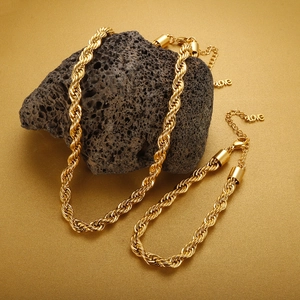 Macro view of 18K gold plated rope chain necklace and bracelet set on volcanic rock