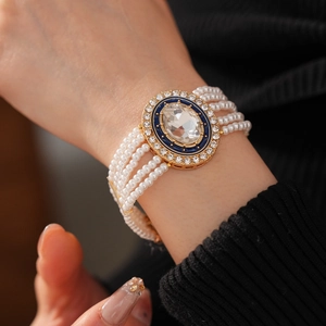 Detail of multi-layer pearl bracelet with blue enamel and crystal pendant on wrist