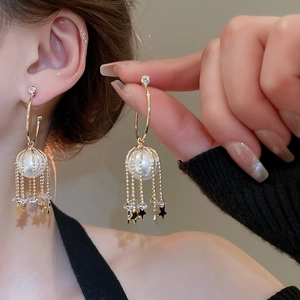 Close-up of pearl tassel star earrings with gold metal chains and zircon details