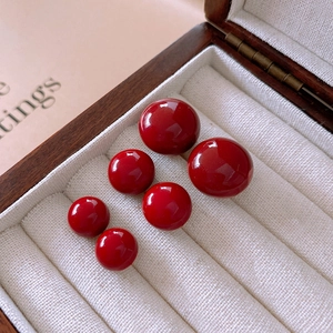 Macro shot of polished round red beads in various sizes inside a wooden jewelry box