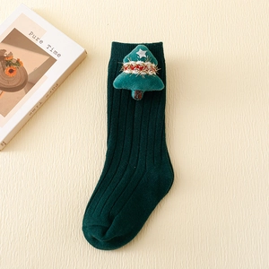 Close-up of green knitted children socks with festive plush Christmas tree decoration