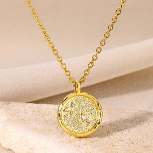 Macro shot of gold-plated zodiac coin necklace with white zircon constellation pattern