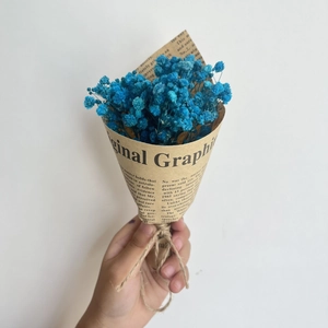 Close-up of mini blue dried baby's breath flower bouquet wrapped in vintage newspaper style paper
