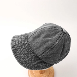 Detail view of stitched brim and washed denim texture of a dark grey sun hat