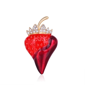 Detailed close-up of a red strawberry brooch with gold metal leaves and inset rhinestones