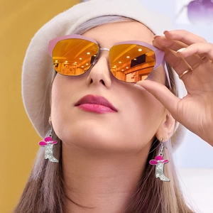Detail of silver cowboy boot earrings with rhinestones and pink hat worn by a model