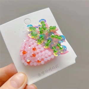 Detailed view of handmade strawberry hair clip featuring sparkling pink beaded embellishments