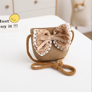 Detail of children's straw shoulder bag featuring a floral bow and white lace trim