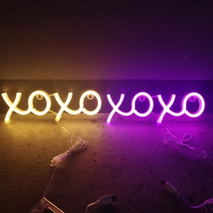 Detail of XOXO neon light showing USB power connection in warm yellow and pink purple colors