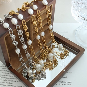 Baroque pearl knot jewelry set with gold and silver steel necklaces on a wooden box