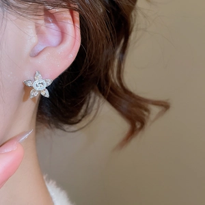 Macro detail of silver flower stud earrings with sparkling crystals on a model's ear