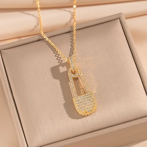 Macro shot of gold safety pin necklace with pavé cubic zirconia in a jewelry box
