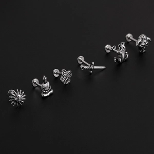 Detail view of six silver stainless steel studs featuring sun, owl, and frog motifs