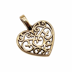 Macro view of vintage bronze heart-shaped charm with intricate filigree pattern detail