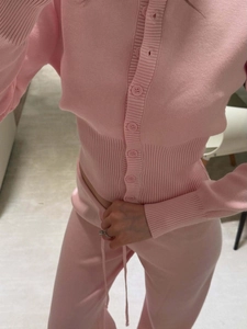 Close-up of pink knit cardigan and trousers set showing soft texture and button details