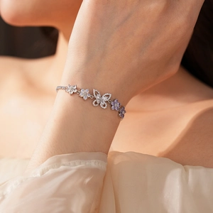 Detailaufnahme eines silbernen Armbands mit violetten Zirkon-Schmetterlingsanhängern